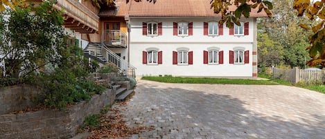 A two-story building with a red-tiled roof, a stone staircase, and a paved courtyard.