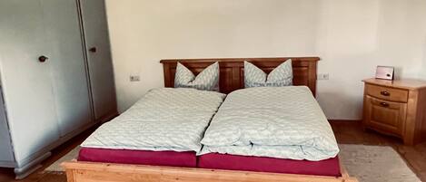 A bedroom with a wooden bed, a wardrobe, a nightstand, and a rug.