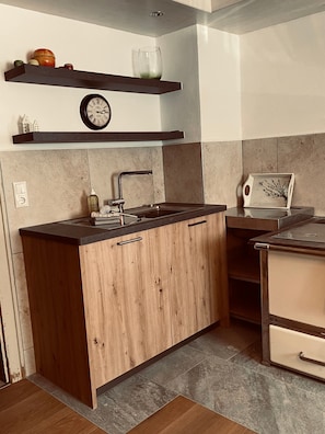 A modern kitchen with a wooden island, a built-in sink, and a clock above the counter. - Farmhouse 'Niederbleick' with Mountain View, Shared Garden and Wi-Fi (Wildsteig)