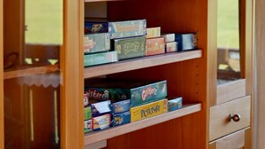 Un mueble de madera con varios compartimentos, algunos con juegos de mesa.
