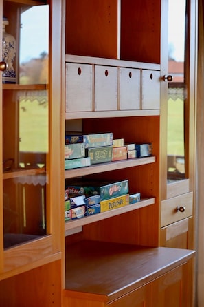 A wooden cabinet with multiple compartments, some containing board games.