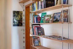 A bookshelf with various books and a framed picture on the wall.