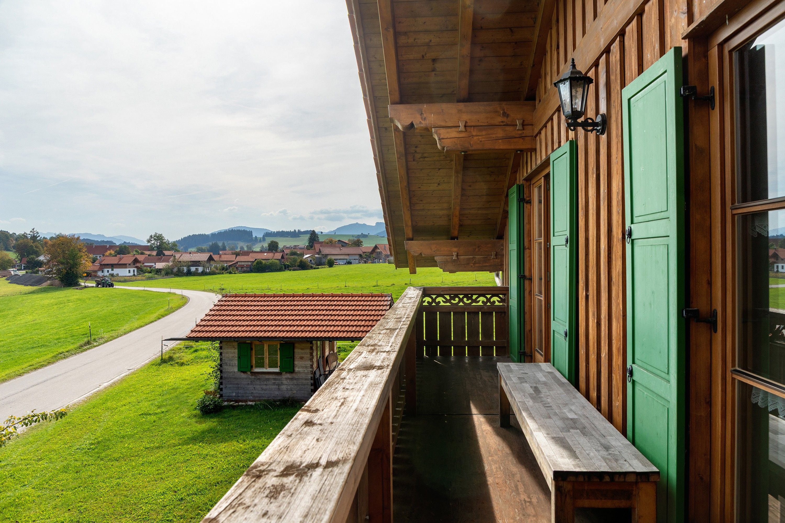 Un edificio de madera con un balcón que da a un paisaje verde y una carretera.