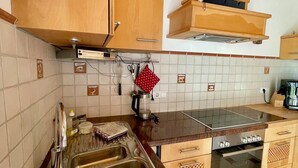 Una cocina con armarios de madera, un lavamanos de acero inoxidable, una estufa y una cafetera.