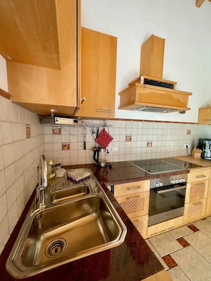 A kitchen with wooden cabinets, a stainless steel sink, a stove, and a coffee maker.