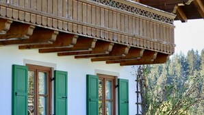 Un edificio de madera con un balcón, contraventanas verdes y techo de tejas.