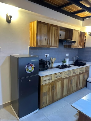 A kitchen with wooden cabinets, a black refrigerator, a stove, and a tiled backsplash.