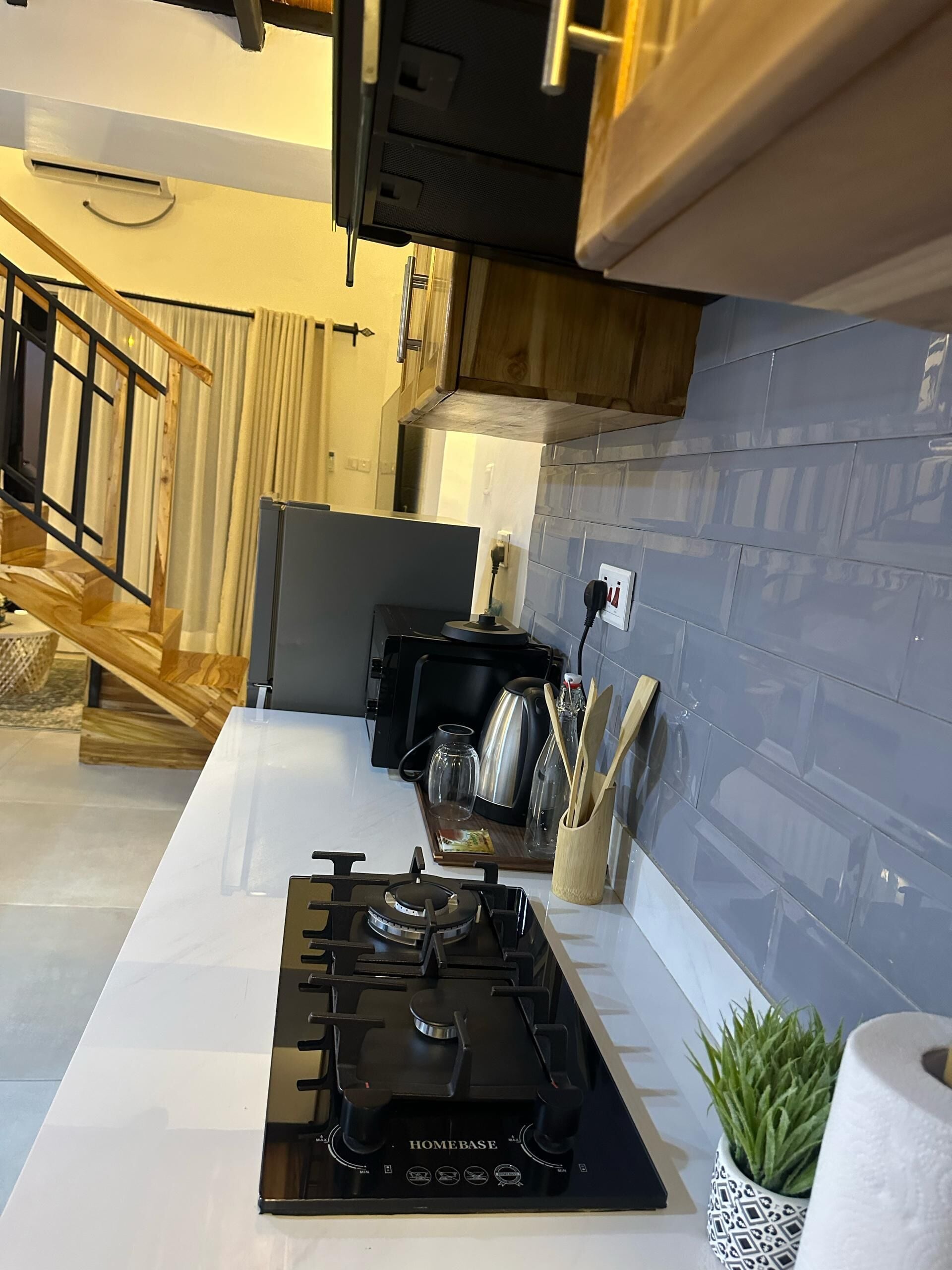 A modern kitchen with a gas stove, wooden cabinets, and a stainless steel kettle.