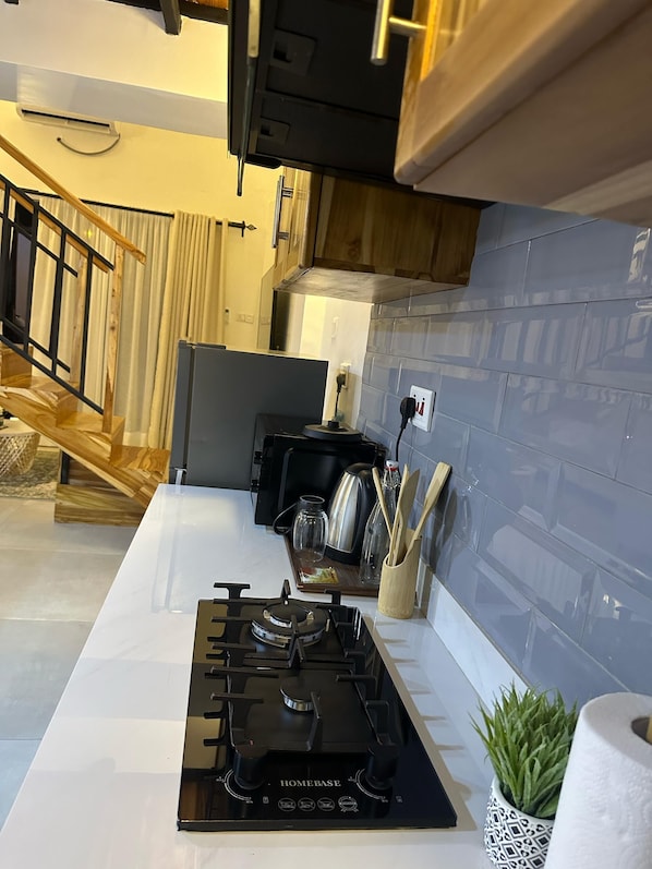 A modern kitchen with a gas stove, wooden cabinets, and a stainless steel kettle.