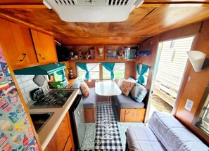 A compact RV kitchen with a stove, sink, and a small dining area. - CANHAM RV & Backyard Spa Experience for 2 (Dover)