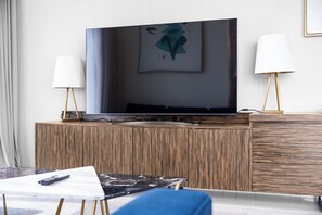 Un salon moderne avec un téléviseur à écran plat posé sur un meuble en bois, une petite table basse et deux lampadaires.