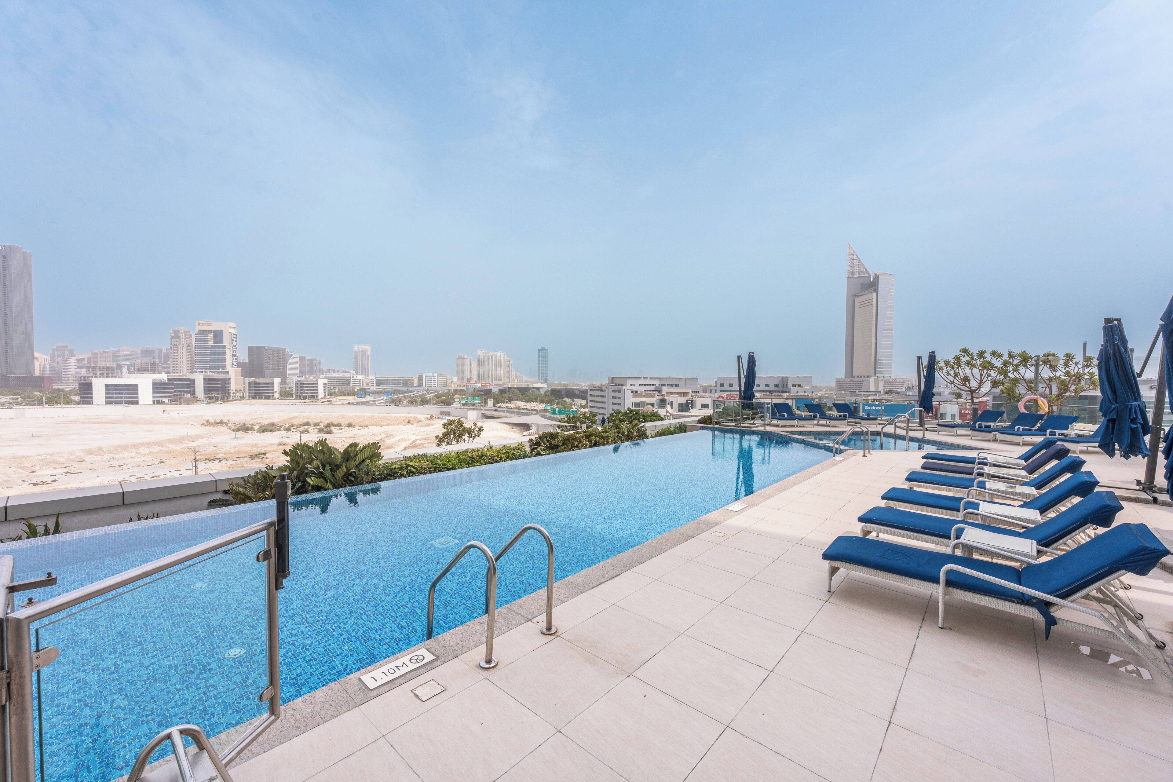 A rooftop pool with lounge chairs and a city view.