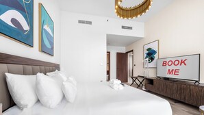 A hotel room with a large bed, a TV, and artwork on the walls. - StayShort - Dubai Media City sleeps 2 with Amazing Sea Views! (Media City)