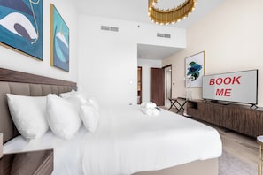 Ein Hotelzimmer mit einem großen Bett, einem Fernseher und Kunstwerken an den Wänden.