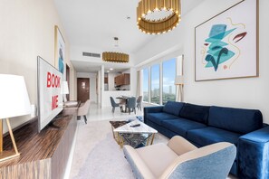 Un salon moderne avec un canapé bleu, une table basse et un coin repas offrant une vue sur la ville.