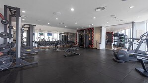 A modern gym with various exercise equipment, including treadmills, weight machines, and free weights. - StayShort - Dubai Media City sleeps 2 with Amazing Sea Views! (Media City)