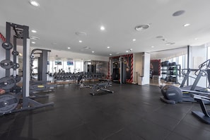 Ein modernes Fitnessstudio mit verschiedenen Trainingsgeräten, darunter Laufbänder, Kraftgeräte und Kurzhanteln.
