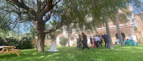 Un espacio al aire libre con césped, un árbol, una mesa de picnic y un edificio al fondo.