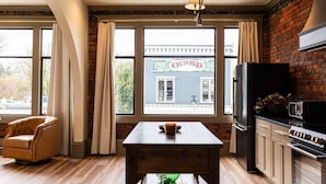Une cuisine avec un mur en briques, une table à manger, une chaise et une vue sur un bâtiment portant l’inscription « OXFORD ».