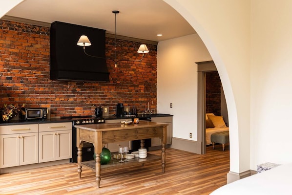A kitchen with a brick wall, wooden cabinets, a central island, and pendant lighting.