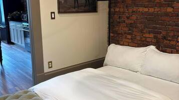 A bedroom with a large bed, a brick wall, and a painting of a horse.