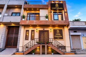 A hotel named 'Hotel Little Ganesha' with a modern facade, a staircase with railings, and multiple potted plants. - Little Ganesha Inn (Jaipur)