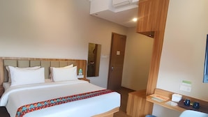 Una habitación de hotel con cama, escritorio, silla y basurero.