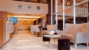 Un moderno vestíbulo de hotel con mostrador de recepción, zona de estar y una escalera.