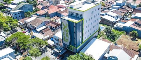 Un edificio moderno con una fachada geométrica distintiva, rodeado por una zona urbana densa con edificios tradicionales.