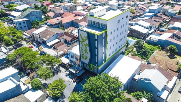 Un edificio moderno con una fachada geométrica distintiva, rodeado por una zona urbana densa con edificios tradicionales.