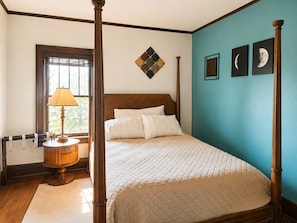 A bedroom with a four-poster bed, a nightstand with a lamp, and a window with blinds. - Classic Fargo Retreat Near NDSU & Downtown (Fargo)