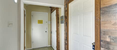 A hallway with a white door, a wooden accent wall, and a trash bin.