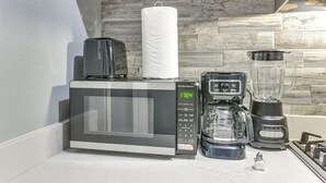 Una cocina equipada con microondas, cafetera, licuadora y estufa.