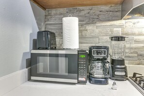 Eine Küche mit Mikrowelle, Kaffeemaschine, Mixer und Herd.