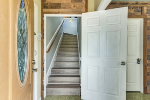A staircase leading to a room with a white door, wooden walls, and a security keypad. - 2-Unit Combo 10 Mi to Vintage Park & Airport! (Houston)