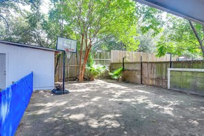 Ein Garten mit einem Basketballkorb, einem Holzzaun und einem Gartenhaus.