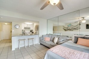 A modern living space with a kitchenette, a dining area, and a bedroom with a large bed and a sofa. - Unwind Poolside, Walk to Shore! Orange Beach Condo (Orange Beach)