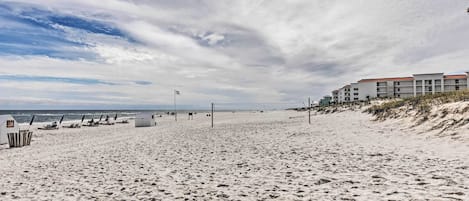 Una playa con una fila de edificios, una red de voleibol y una torre de salvavidas.