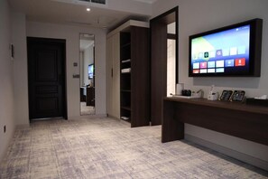 A hotel reception area with a flat-screen TV displaying a digital interface, a reception desk, and a mirror reflecting the room. - Wantong Central Park Hotel (Jalal-Abad)