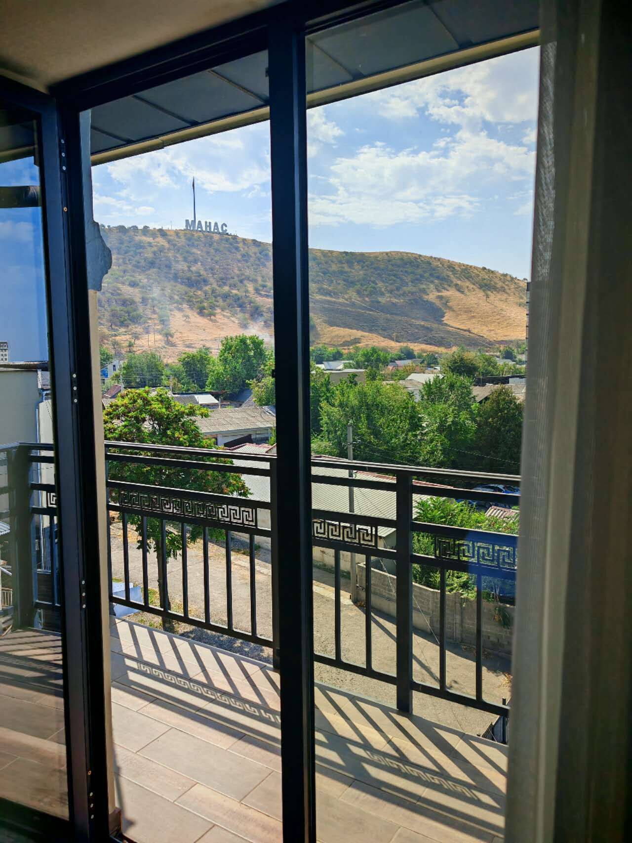 A balcony with a view of a hill and a structure with 'MAHAC' on it.