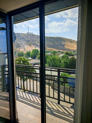 A balcony with a view of a hill and a structure with 'MAHAC' on it. - Wantong Central Park Hotel (Jalal-Abad)