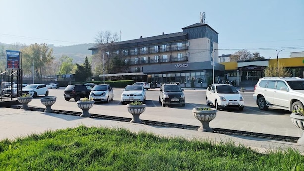 Un edificio con un cartel que dice 'MOIKO' y varios coches estacionados en la parte delantera.