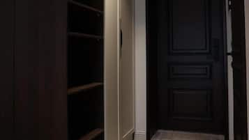 A hallway with a dark wooden wardrobe, a door with a panel design, and a patterned carpet.
