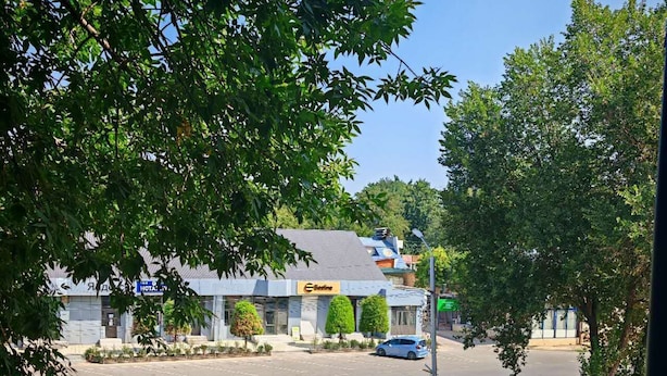 A hotel with a parking lot, a building with a sign, and trees in the foreground.