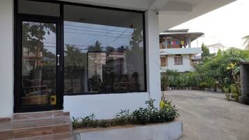 A modern building with a large glass door and windows, a concrete pathway, and a small garden area.