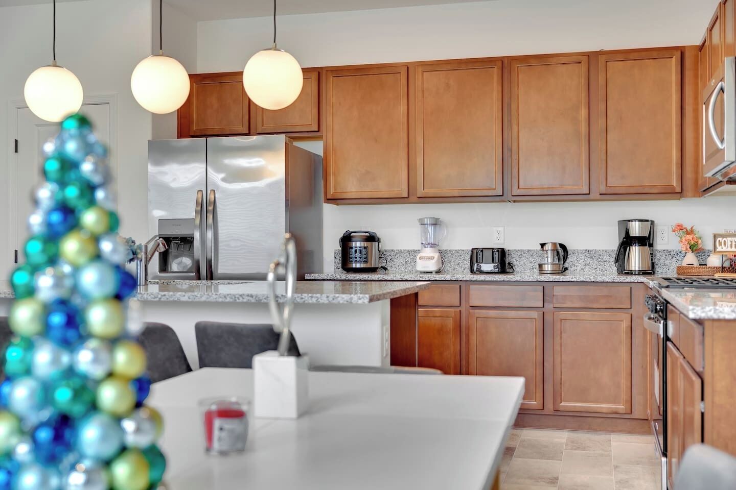 Cocina moderna con armarios de madera, electrodomésticos de acero inoxidable y encimera de granito.