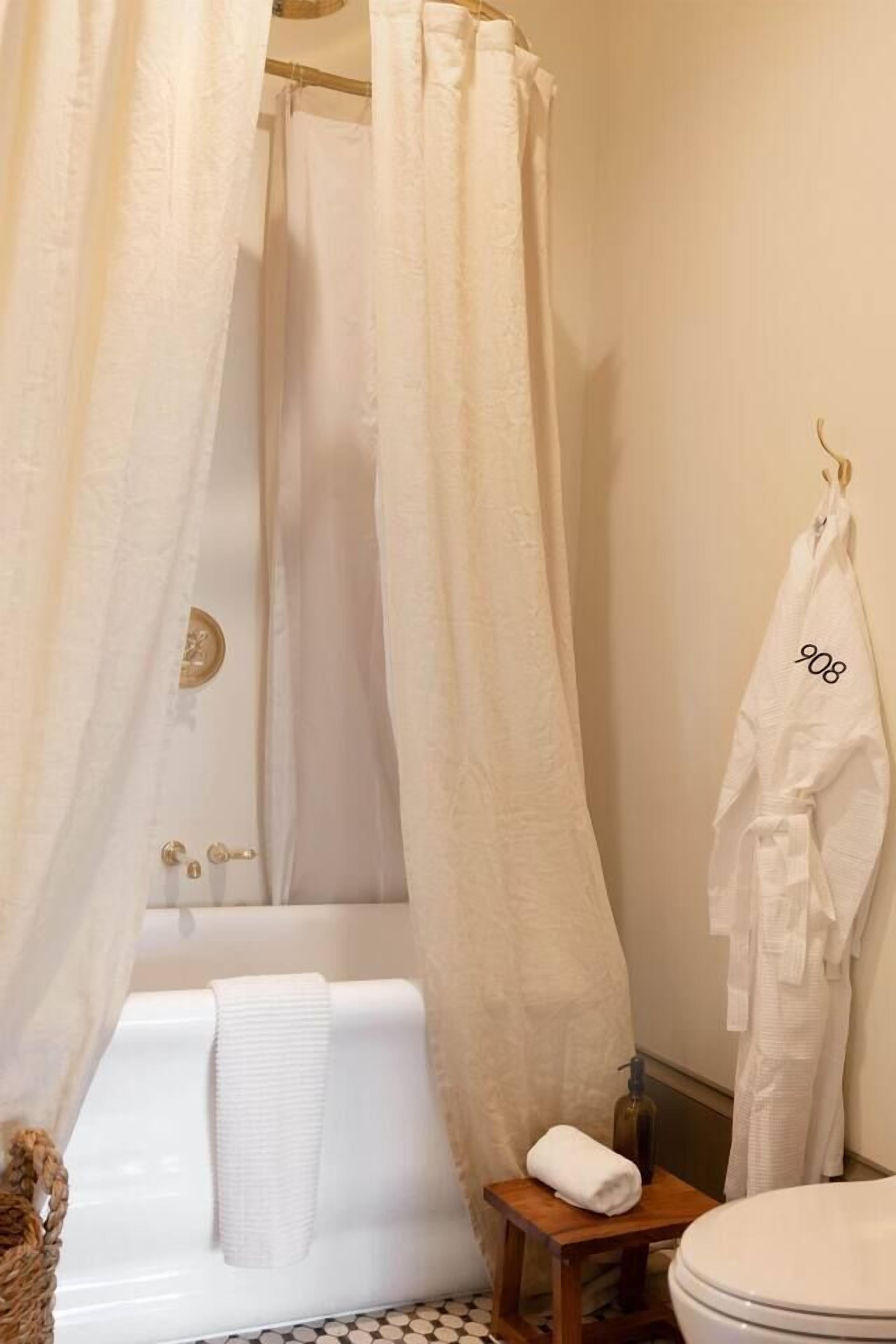 Ein Badezimmer mit einer Badewanne, einer Duschvorhang, einem Handtuchhalter und einem kleinen Holzschemel.