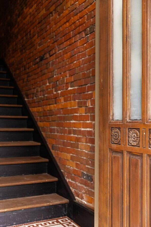 A staircase with a brick wall on one side and a wooden door with glass panels on the other.