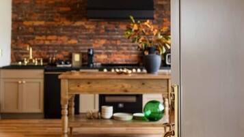 A modern kitchen with a brick wall, wooden flooring, and a black range hood.