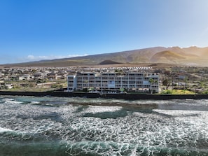 Ein Küstenhotel mit mehreren Etagen, einem Schwimmbad und Blick auf den Ozean und die Berge.